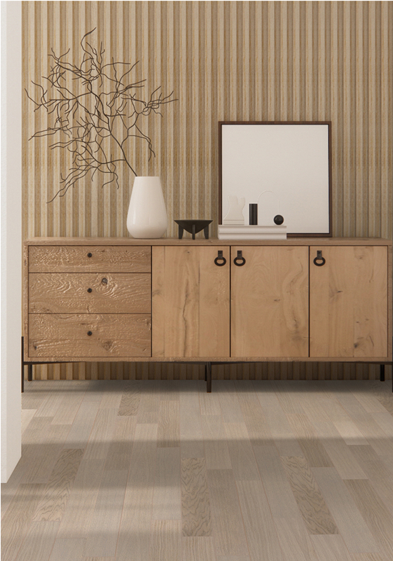 A minimalist wooden sideboard with black handles sits against a striped beige wall, topped with a white vase holding bare branches, decorative objects, and a framed mirror. Smart floors in light wood complete the space.