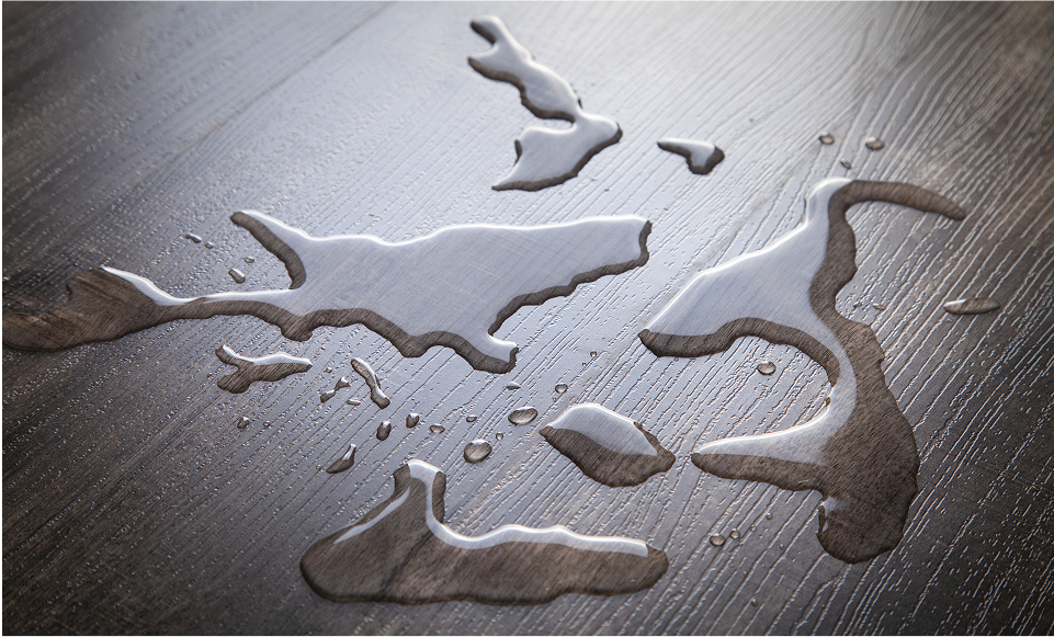 Water droplets and small puddles scattered on a dark wooden smart floor, reflecting light and creating abstract shapes.