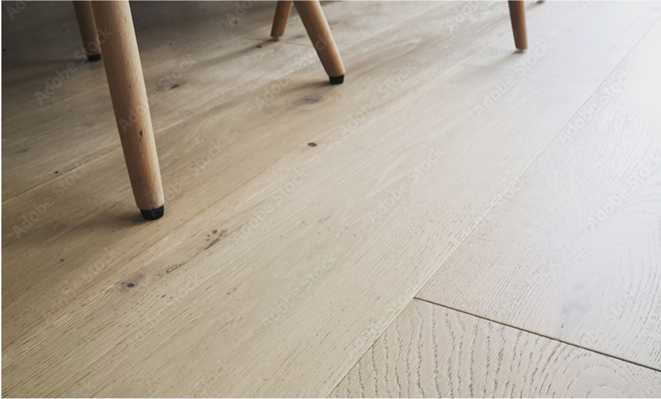 Close-up view of smart floors featuring light-colored wood with a natural grain pattern and smooth finish. Part of a table and chair leg is visible in the top left corner, highlighting the modern appeal.