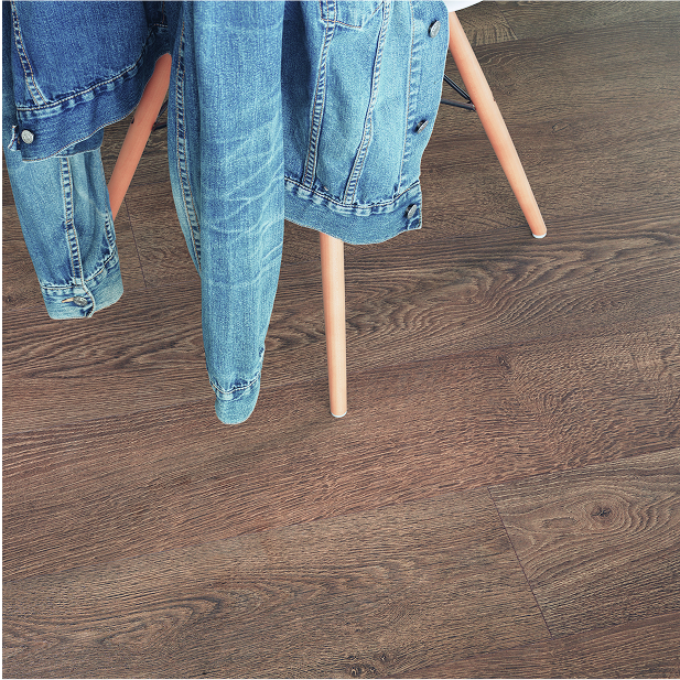 A denim jacket is draped over the back of a wooden chair with light-colored legs, set on smart floors featuring a brown wood-grain finish.