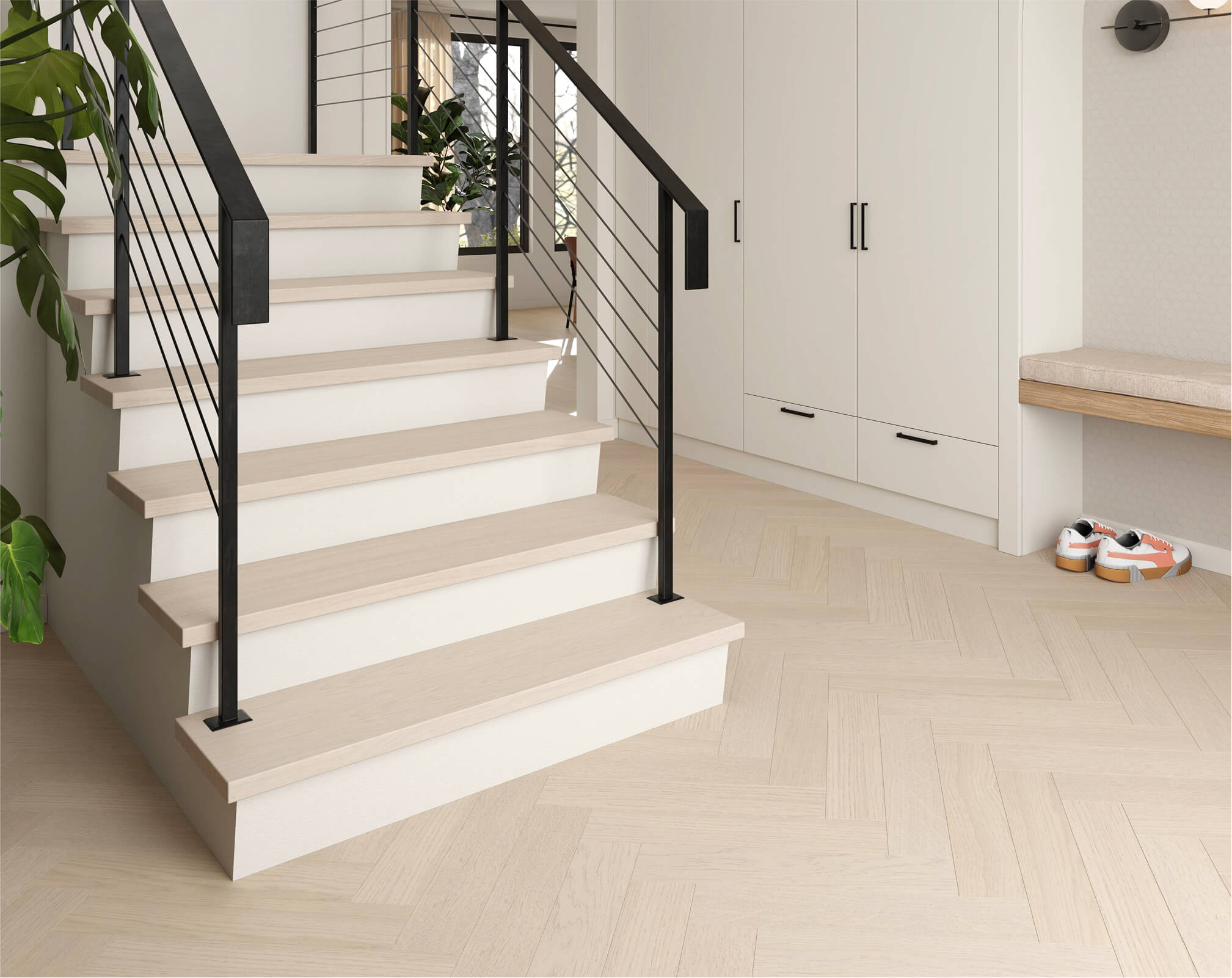 A modern entryway with light wood stairs and black railing, beige herringbone smart floors, white cabinets, a built-in bench, and a pair of sneakers on the floor. Green plants are visible to the left.
